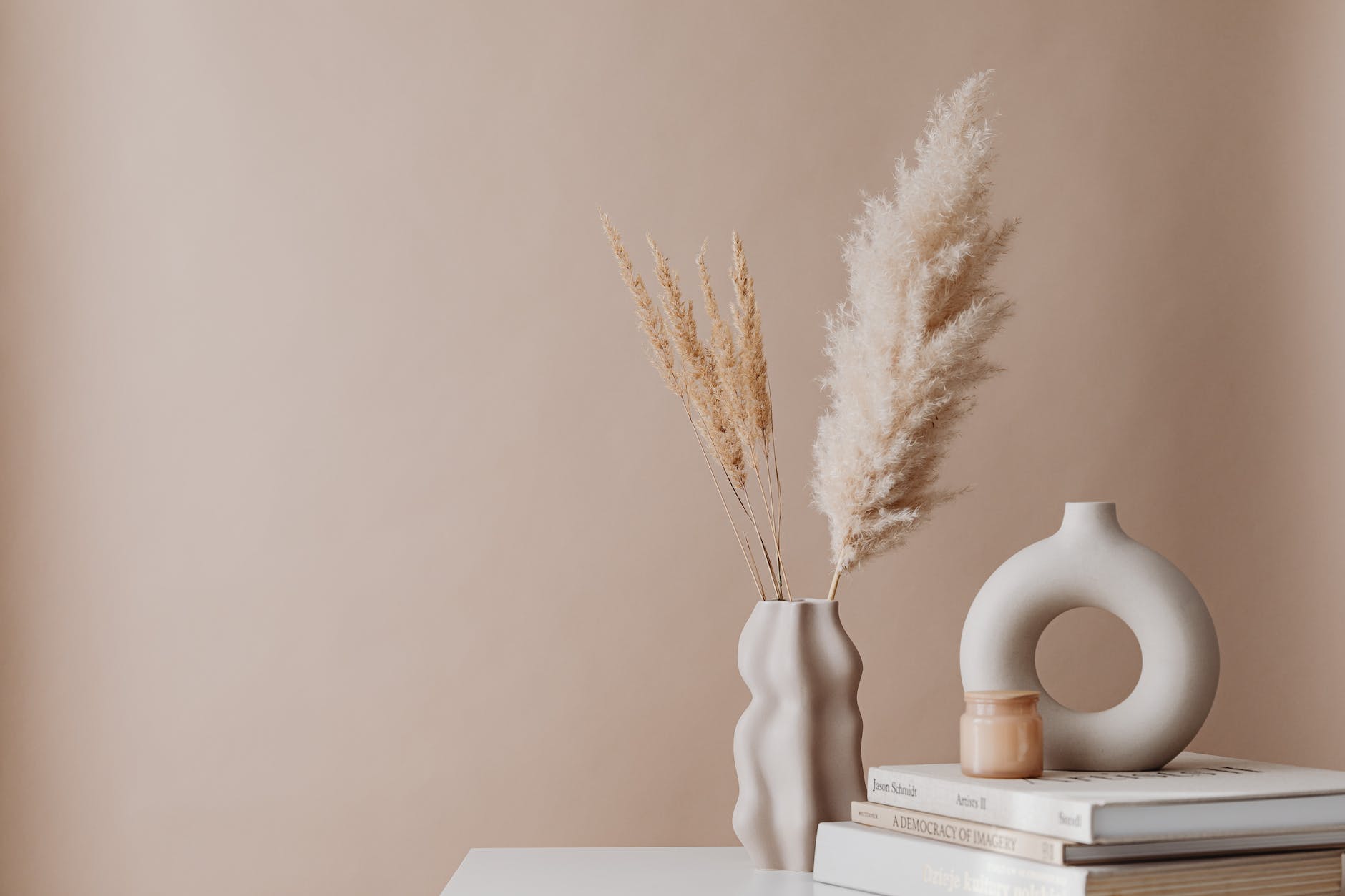 beige minimalistic decor dry grass in a vase candle and books